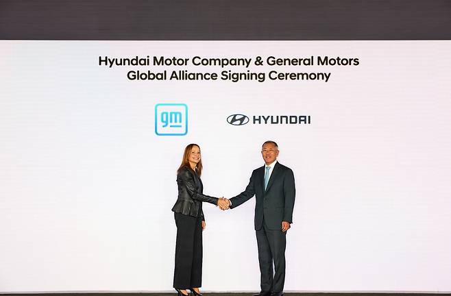 Hyundai Motor Group Executive Chair Euisun Chung, right, shakes hands with General Motors CEO Mary Barra after signing an agreement pledging cooperation in automobile development in New York. [HYUNDAI MOTOR]