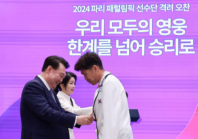 윤석열 대통령과 김건희 여사가 13일 청와대 영빈관에서 열린 '2024 파리 패럴림픽 선수단 격려 오찬'에서 트라이애슬론 김황태 선수와 아내인 경기보조인 김진희 씨에게 국민감사 메달을 수여하고 있다./연합