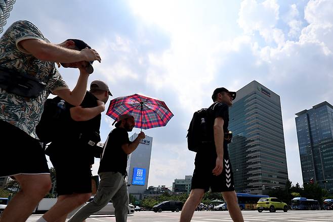 지난 11일 오후 서울 광화문네거리에서 관광객들이 양산과 모자로 햇빛을 가리며 걸음을 옮기고 있다. /뉴스1