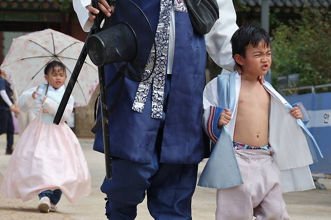 추석 연휴 마지막 날인 18일 오후 서울 종로구 경복궁에서 한복입은 한 어린이가 저고리를 풀며 더위를 식히고 있다. 기상청은 이날 오전 강원도와 경기도 북부를 제외한 전국 대부분 지역에 폭염 특보를 발효했다. 김혜윤 기자 unique@hani.co.kr