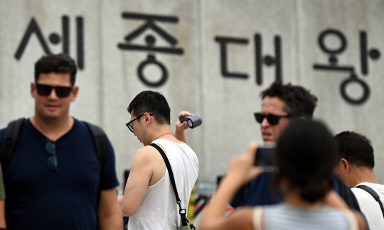 폭염이 계속 되고 있는 가운데 추석 연휴 마지막 날인 18일 서울 광화문 광장에서 한 관광객이 휴대용선풍기로 더위를 식히고 있다.  박윤슬 기자