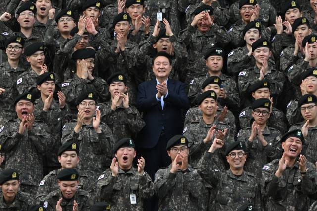 ▲윤석열 대통령이 추석인 17일 강원도 최전방 육군 15사단 사령부 사열대에서 사단 장병들과 기념촬영을 마치며 박수를 치고 있다. 윤 대통령 오른쪽 아래는 육군 15사단 군악대에서 복무 중인 방탄소년단(BTS) 리더 김남준(RM) 상병. ⓒ연합뉴스