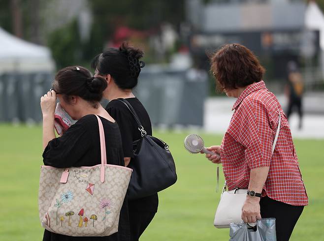 기록적인 늦더위가 이어진 19일 오후 서울 광화문광장을 찾은 시민들이 손수건으로 땀을 닦고 있다. 연합뉴스