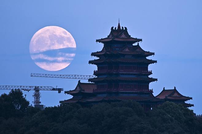 [난징=AP/뉴시스] 17일(현지시각) 중국 장쑤성 난징에서 중추절 축제가 열리는 동안 전통 건물 뒤로 보름달이 뜨고 있다. 이번 보름달은 달과 지구 사이의 거리가 35만8211㎞로 평균 거리보다 가까워 더 밝고 큰 슈퍼문이다. 2024.09.18