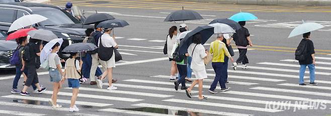 절기상 추분을 이틀 앞둔 20일 서울 종로구 흥인지문사거리에서 시민들이 우산을 받쳐들고 길을 건너고 있다.