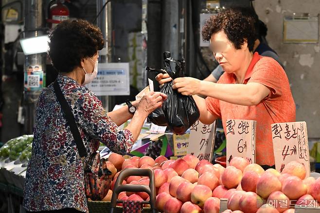 6일 오전 서울 동대문구 경동시장을 찾은 한 시민이 과일을 구매하고 있다. 임세준 기자