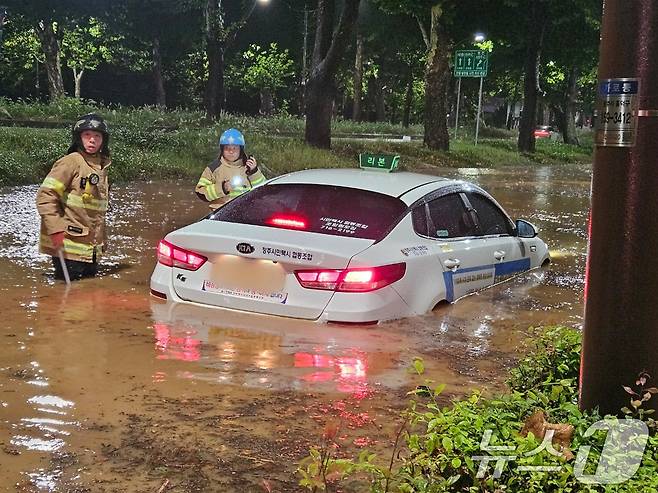 21일 오전 충북 청주시 석소동에서 집중호우로 인해 도로가 침수되어 출동한 소방대원들이 고립된 택시차량을 이동 조치하고 있다. (소방청 제공) 2024.9.21/뉴스1