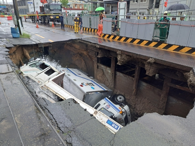 21일 부산 사상구 학장동의 한 도로에서 트럭 2대가 땅꺼짐 현상(싱크홀)으로 인해 발생한 구멍에 빠졌다. 부산소방본부 제공