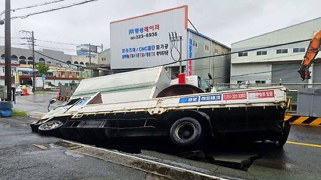 부산 사상구 한 도로에서 가로 10ｍ, 세로 5ｍ, 깊이 8m가량의 대형 싱크홀이 발생해 트럭이 빠져 있다.