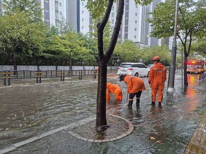 집중호우가 이어지고 있는 21일 경남 양산시 물금읍 증산리 일대 도로가 침수되자 소방대원들이 배수 작업을 하고 있다. 경남소방본부 제공