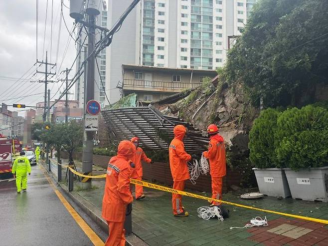 지난 21일 오전 호우경보가 발효된 부산 사상구 학장동의 한 건물 벽이 집중호우로 인해 무너졌다는 신고가 접수돼 출동한 소방과 경찰이 인근 도로를 통제하고 있다. ⓒ부산소방재난본부/뉴시스