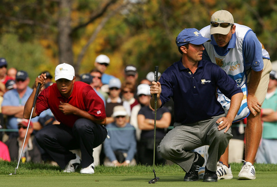 Mike Weir and his caddie Brennan Little of the International Team look over a putt as Tiger Woods of the U.S. Team looks on during the final day of 2007 The Presidents Cup at The Royal Montreal Golf Club in Montreal, Canada on Sept. 30, 2007.  [GETTY IMAGES]