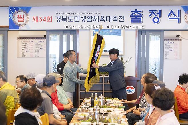 울릉군은 지난 23일 ‘제34회 경북도민생활체육대축전’출정식을 가진 가운데 공호식(왼쪽) 울릉군체육회회장이 선수단 대표에게 울릉군 기를 전달하며 필승을 기원하고 있다. 