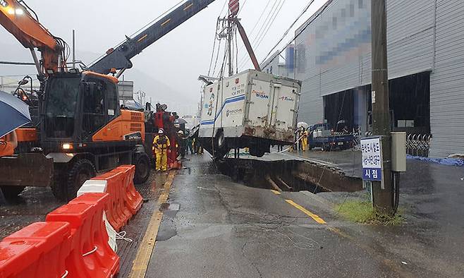 지난 21일 부산 사상구의 한 도로에서 발생한 땅꺼짐(싱크홀)에 빠졌던 소방배수지원차가 인양되고 있다. 부산소방재난본부 제공