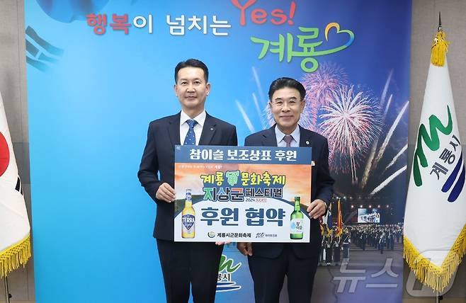 이승용 (주)하이트진로 특판 대전지점장(왼쪽)이 이응우 계룡시장과 군문화축제 홍보를 위한 ‘소주병 보조상표 후원 전달식’을 갖고 기념촬영을 하고 있다. (계룡시 제공) /뉴스1