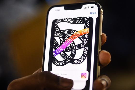 A technology company employee downloads the newly unveiled Threads app on a mobile phone in July 2023. Threads is a text-based social media app launched by Meta. Many online communities in Korea are text-based, with a number of them offering image and video posts as well. [EPA/YONHAP]