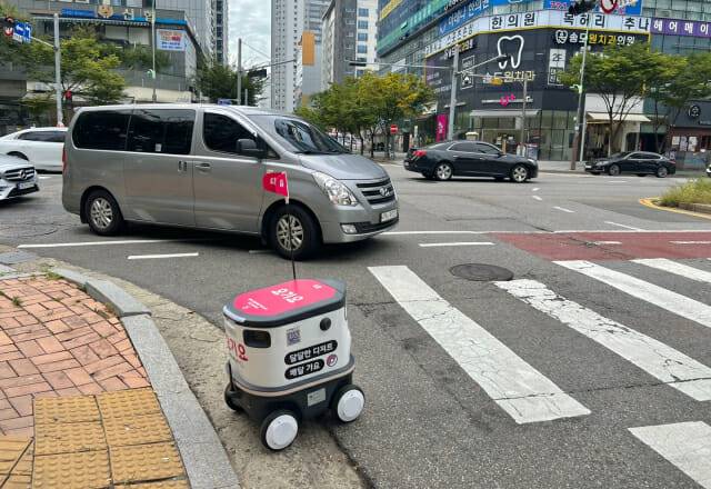 뉴빌리티X요기요 배달로봇 '뉴비'가 인천 송도 일대에서 배달 업무를 수행 중이다. 우회전해 들어오려던 차량을 마주해 서로 양보하고 있는 모습이다. (사진=지디넷코리아 신영빈 기자)