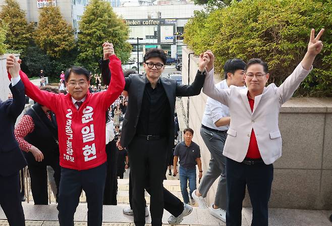 한동훈 국민의힘 대표가 27일 부산 금정구 옛 침례병원을 찾아 윤일현 후보와 박수영 부산시당위원장과 함께 손을 들어보이고 있다. 연합뉴스