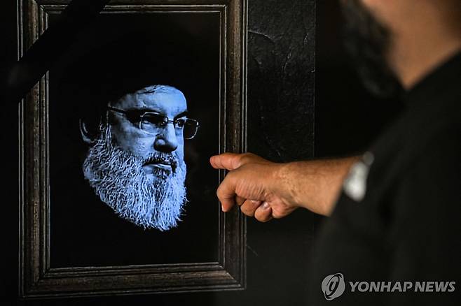 이스라엘군 공격으로 사망한 헤즈볼라 최고지도자 하산 나스랄라의 TV 영상을 가리키는 남성 [AFP 연합뉴스. 재판매 및 DB 금지]