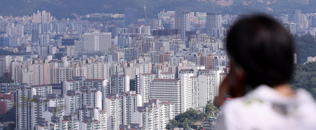 지난달 25일 서울 남산을 찾은 관광객이 시내와 아파트 단지를 바라보고 있다. 뉴스1