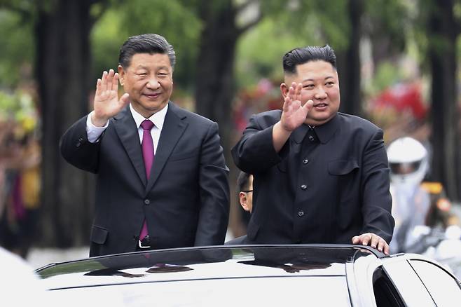 In this file photo released by China's Xinhua News Agency on Sunday, visiting Chinese President Xi Jinping (left) and North Korean leader Kim Jong Un wave from an open top limousine as they travel along a street in Pyongyang, North Korea, on June 20, 2019. (Xinhua via AP)