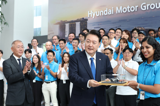 President Yoon Suk Yeol, center, visits Hyundai Motor Group Innovation Center in the Jurong Innovation District in Singapore on Wednesday, accompanied by Hyundai Motor Group Executive Chair Euisun Chung, left. Yoon is receiving an Ioniq model car as a souvenir. [JOINT PRESS CORPS]