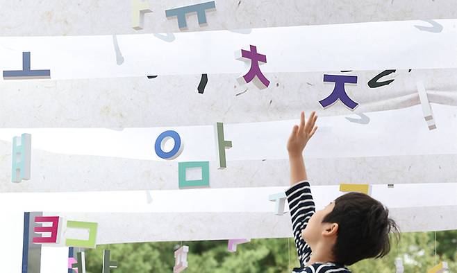 577돌 한글날인 지난 2023년 10월 9일&nbsp;서울 용산구 국립 한글박물관에 마련된 통로에서 한 아이가 매달린 한글 전시물을 잡으려 하고 있다. 연합뉴스