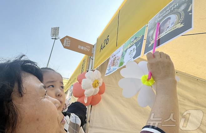 12일 오전 10시께 찾은 전북 전주종합경기장에서 최 모 씨(67·전주)가 손녀딸을 안고 '한강 작가'를 알려주는 모습. 2024.10.12/뉴스1 장수인 기자