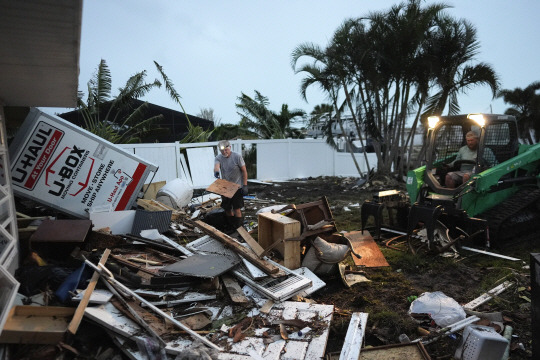 <YONHAP PHOTO-1740> Homeowner Robert Turick, 68, left, and storm waste removal contractor Sven Barnes work to clear debris that Hurricane Milton storm surge swept from other properties into Turick‘s canal-facing back yard, in Englewood, Fla., Friday, Oct. 11, 2024. Turick, whose family has owned the home for more than 25 years, said it had never flooded until 2022’s Hurricane Ian, but since then, it has flooded in three more hurricanes, each bringing higher water levels than the last. (AP Photo/Rebecca Blackwell)/2024-10-12 09:39:21/<저작권자 ⓒ 1980-2024 ㈜연합뉴스. 무단 전재 재배포 금지, AI 학습 및 활용 금지>