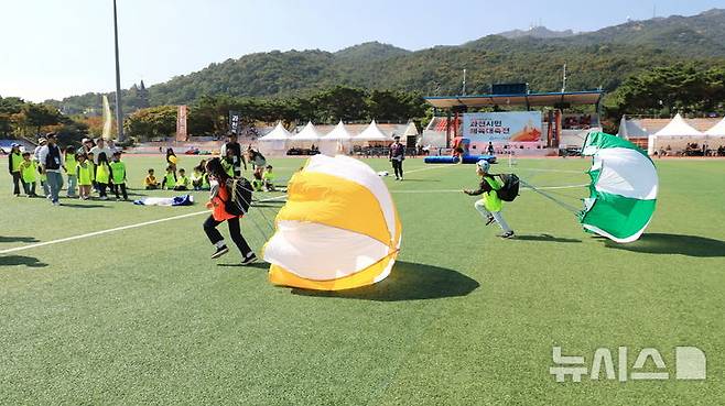 [과천=뉴시스] 체육대회에 참석한 어린이들이 가족들과 함께 '낙하산 달리기'를 하고 있다. (사진=과천시 제공).  2024.10.12. photo@newsis.com. *재판매 및 DB 금지