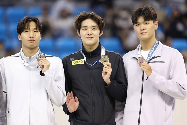 12일 오후 경남 창원시 창원실내수영장에서 열린 제 105회 전국체육대회 남자 일반부 자유형 1500m에서 우승한 김우민(가운데)이 메달을 들어 보이고 있다. 왼쪽부터 장규성, 김우민, 윤준상.  2024.10.12 ksm7976@yna.co.kr 연합뉴스