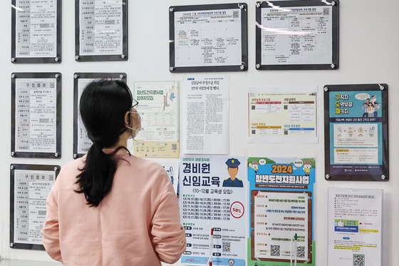 A female job seeker browses through a job bulletin board at a center in Mapo District in western Seoul on Monday. [NEWS1]