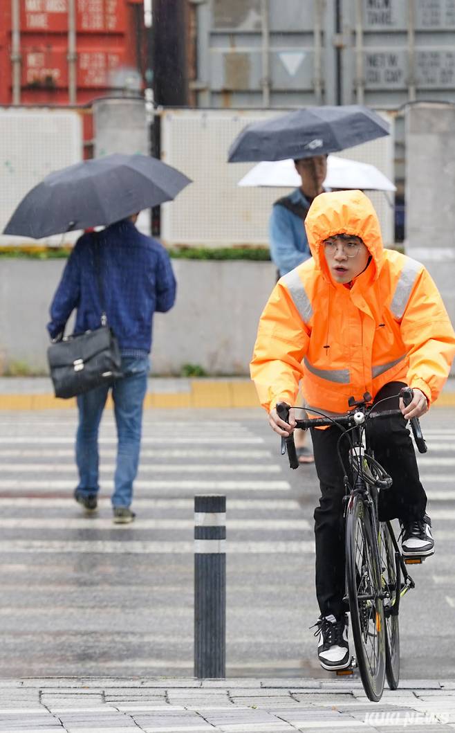 서울 대부분 지역에서 오전 한때 비가 내린 15일 서울 구로구 가산디지털단지역 근처에서 한 시민이 우의를 걸친 채 이동하고 있다.