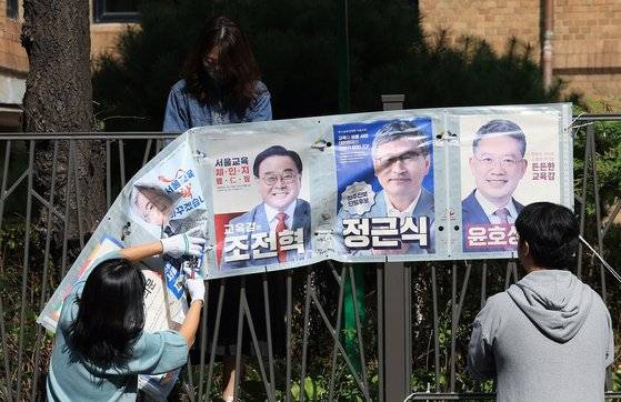 서울특별시 선거관리위원회 직원들이 17일 오전 서울 종로구 동숭길 예술가의 집 담장에 설치된 교육감보궐선거 관련 선거벽보를 철거하고 있다. 뉴스1