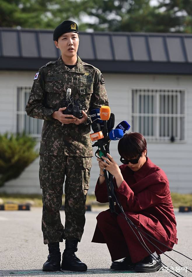 방탄소년단(BTS) 멤버 제이홉(왼쪽)이 17일 강원 원주 36보병사단 신병교육대대에서 전역 소감을 말하고 있는 가운데 진이 직접 마이크 더미를 들고 그의 곁을 지키고 있다.  원주 ｜ 주현희 기자 teth1147@donga.com