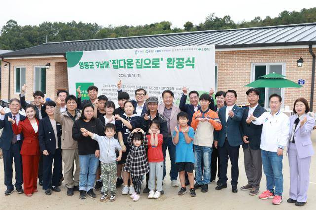 충북도와 영동군, 충북개발공사 관계자들과 주민들이 19일 충북 영동군 심천면 9남매 다둥이 가족을 찾아 새집 완공을 축하고 있다. 이달 말쯤 입주할 이 집은 지역 기업 단체 등 각계의 후원으로 신축됐다. 충북도 제공
