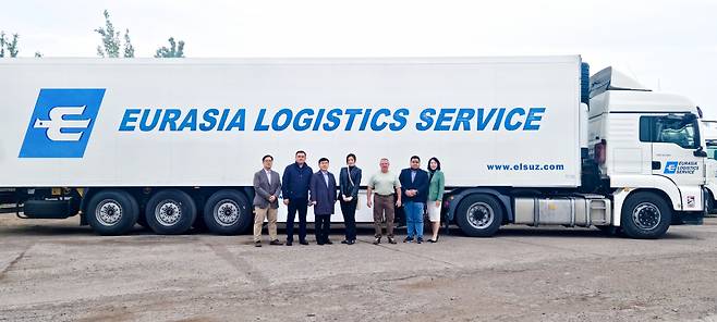 Hanjin Logistics CEO Noh Sam-sug (third from left) and President and Chief Marketing Officer Emily Cho (center) pose for a photo with other officials in front of an Eurasia Logistics Service truck in Uzbekistan. (Hanjin Group)