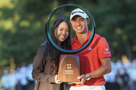 Collin Morikawa poses his wife Katherin Zhu after winning the tournament on the 18th green during the final round of Zozo Championship at Accordia Golf Narashino Country Club on Oct. 22, 2023 in Chiba, Japan. [GETTY IMAGES]