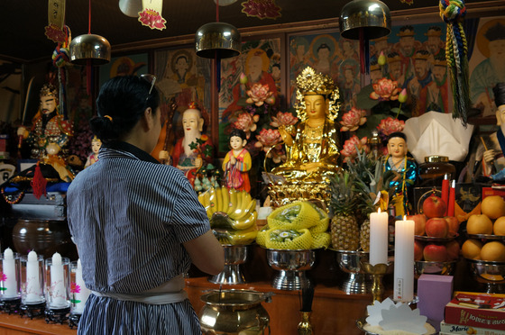 Shaman Kim Jung-hee prays at her shindang, or shrine, inside her home in Seoul. [KIM JU-YEON]