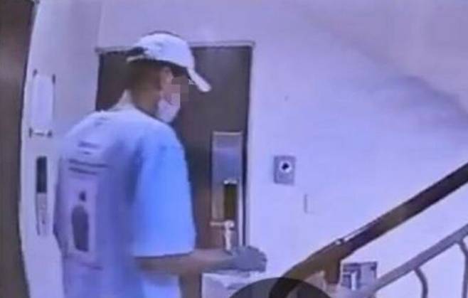 이달 초 울산의 한 다세대주택에서 고무 장갑을 낀 A씨가 B씨의 집 현관문 앞에 서있는 모습. MBC 보도화면 갈무리