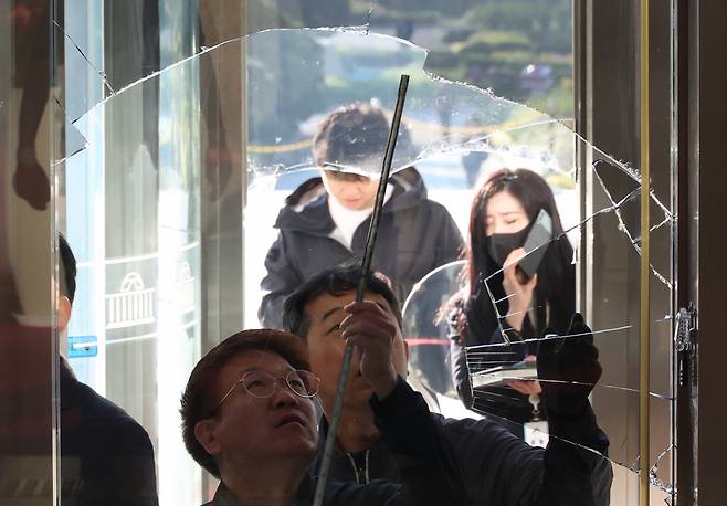 Officials inspect a vandalized entrance gate at the main building of the National Assembly in Yeouido, Seoul, on Friday. (Newsis)