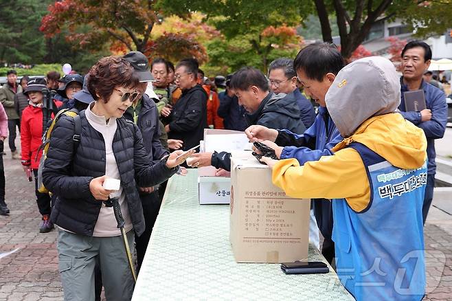 완연한 가을 날씨를 보인 26일 백두대간 두타산 자락 동해 무릉계곡을 방문한 단풍객들이 인근에서 열린 산삼심기 대회에 참가하기 위해 묘삼을 받아가고 있다.(동해시 제공) 2024.10.26/뉴스1