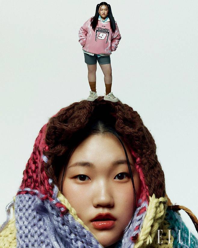 핑크 칼라 니트 톱과 머리에 두른 멀티컬러 니트 톱은 모두 Roynine. 이너 웨어로 입은 스트라이프 셔츠는 Hydrogen. 이너 웨어로 입은 후디드 집업은 Langer. 슈즈는 Ouder. 팬츠와 삭스는 모두 스타일리스트 소장품. 해골 링은 모델 소장품.