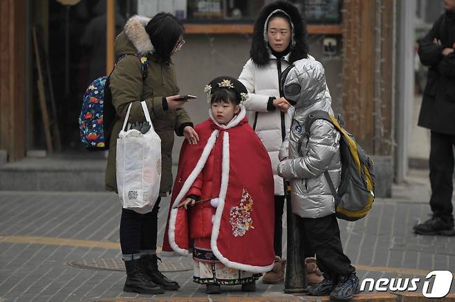 17일 베이징의 한 거리에 엄마와 아이가 서있다. 2024.1.7 ⓒ AFP=뉴스1 ⓒ News1