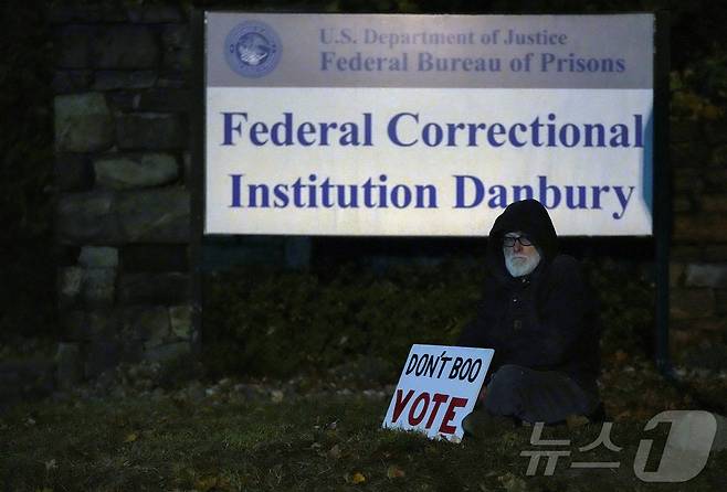 민주주의 운동가이자 기후변화 활동가인 빌 크리스테슨이 2024년 10월 29일 미국 코네티컷주 댄버리에 있는 미국 연방 교도소 앞에서 '투표를 야유하지 말라'고 쓴 손팻말을 들고 전 트럼프 고문 스티브 배넌이 석방되기를 기다리고 있다 ⓒ 로이터=뉴스1