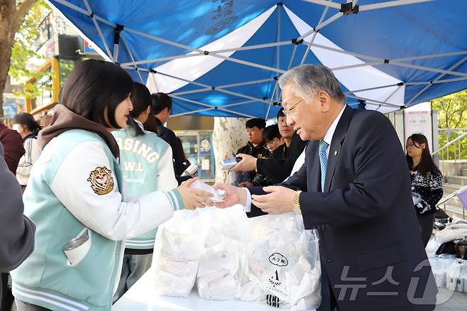 청주대 김윤배 총장(오른쪽)이 30일 중앙도서관 앞 중문에서 총학생회와 단과대학학생회 간부들과 함께 학생들에게 간식을 나눠주고 있다.(청주대 제공)/뉴스1