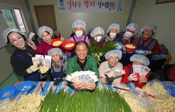 지난 29일 충북 청주 육거리종합시장에 있는 일하는 밥퍼 작업장에서 소윤호 육거리시장 상인회장(앞줄 오른쪽에서 3번째)이 참여자들과 함께 온누리상품권과 쪽파를 들고 웃고 있다. 프리랜서 김성태