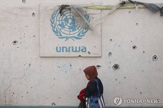 총탄 자국이 가득한 요르단강 서안 대피소 벽면에 부착된 팔 난민구호기구 로고 [AFP 연합뉴스 자료사진. 재판매 및 DB 금지]