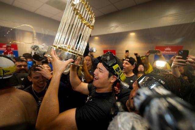 LA 다저스의 간판타자 오타니 쇼헤이가 생애 첫 빅리그 가을야구에서 정상에 선 후 트로피를 들어 올리며 기뻐하고 있다. 뉴욕=AP 연합뉴스