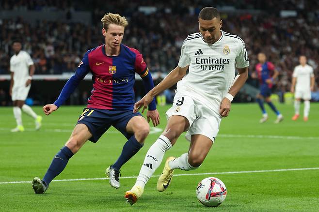 TOPSHOT - Real Madrid's French forward #09 Kylian Mbappe (R) fights for the ball with Barcelona's Dutch midfielder #21 Frenkie De Jong during the Spanish league football match between Real Madrid CF and FC Barcelona at the Santiago Bernabeu stadium in Madrid on October 26, 2024. (Photo by Pierre-Philippe MARCOU / AFP) <저작권자(c) 연합뉴스, 무단 전재-재배포, AI 학습 및 활용 금지>